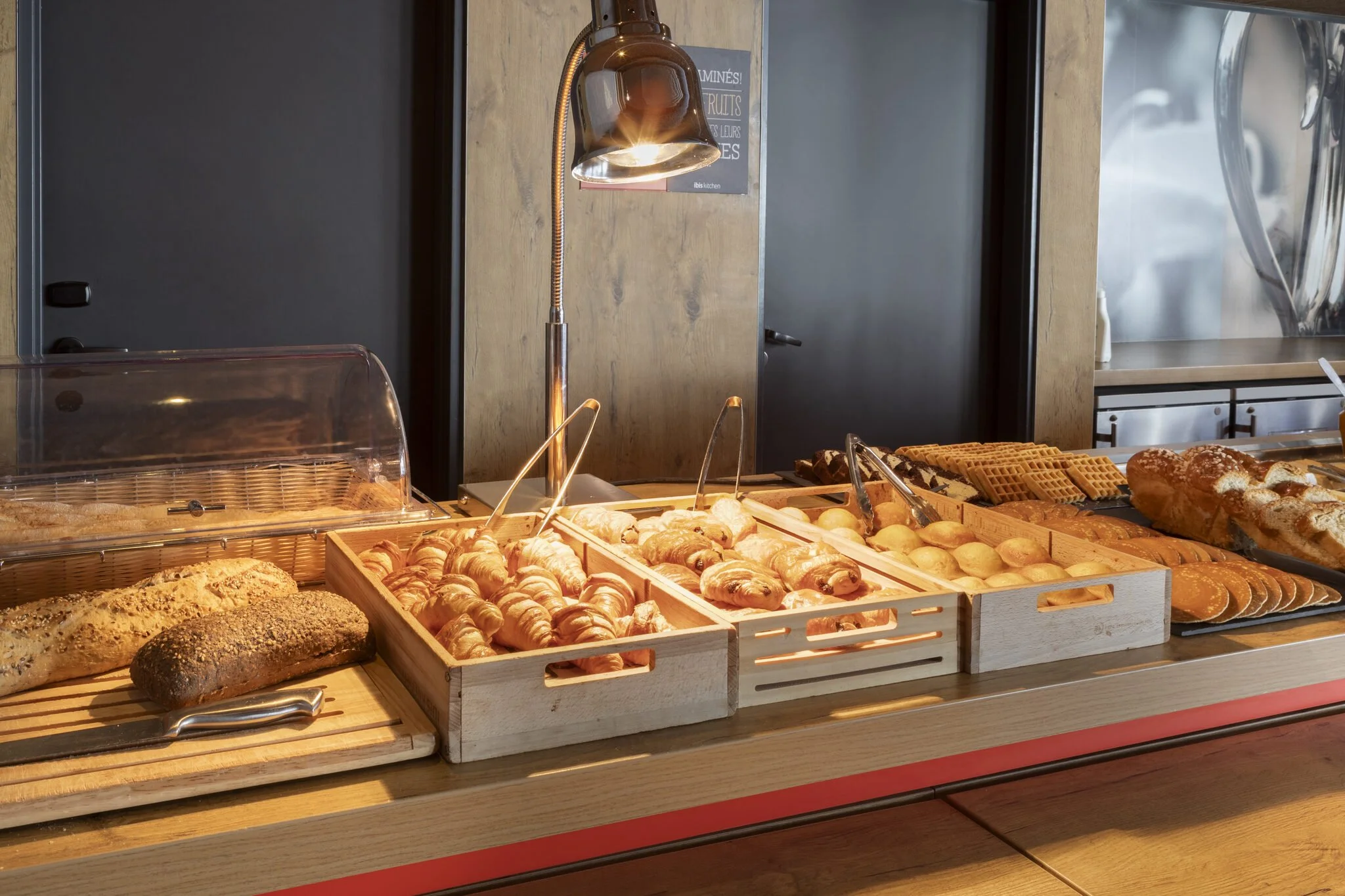 A display case of pastries and breads, featuring croissants, breads, waffles, and other baked goods in a bakery.