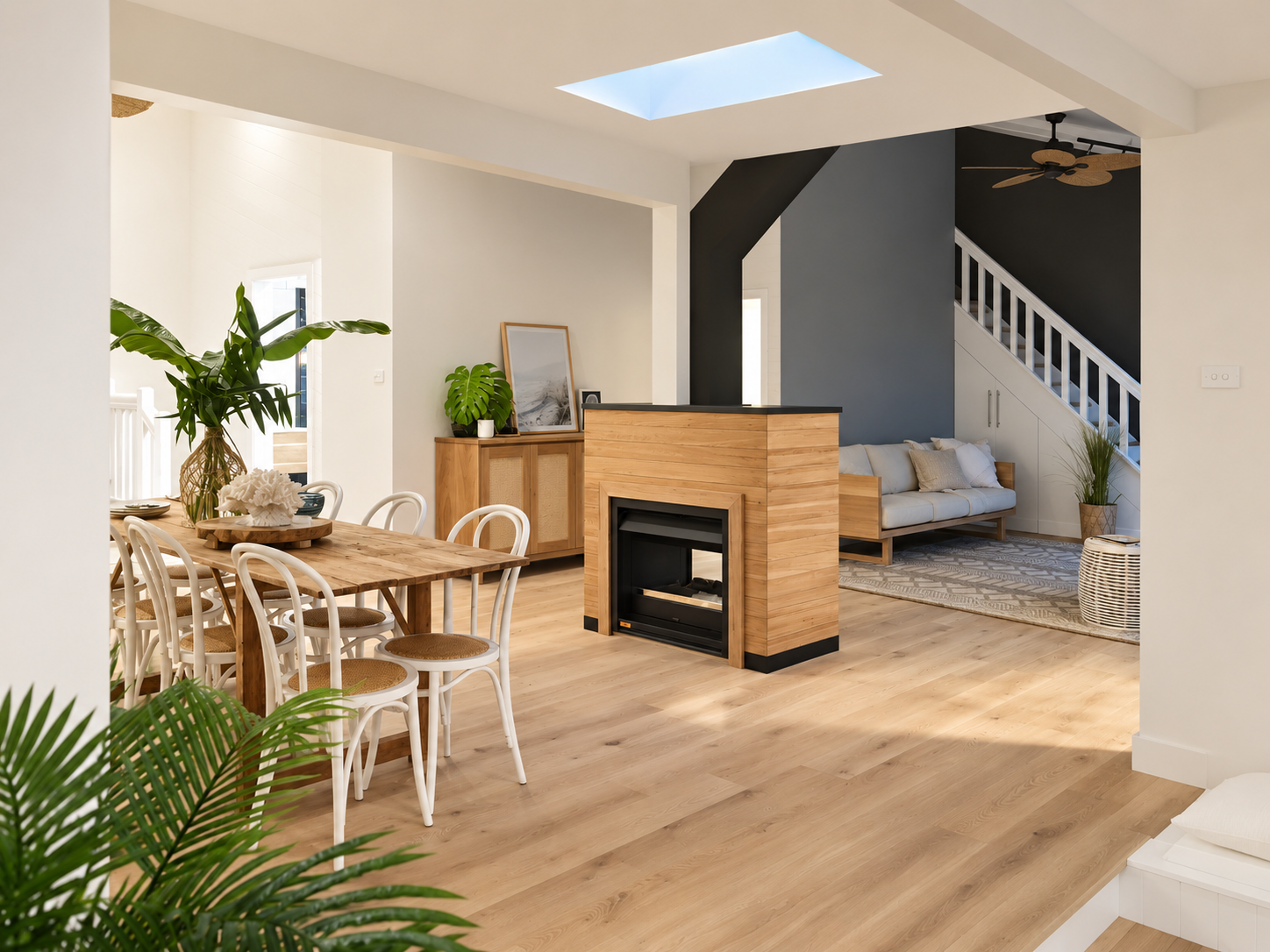 Open-concept living and dining room with white and black walls, wooden furniture, indoor plants, a fireplace, and a staircase leading upstairs.