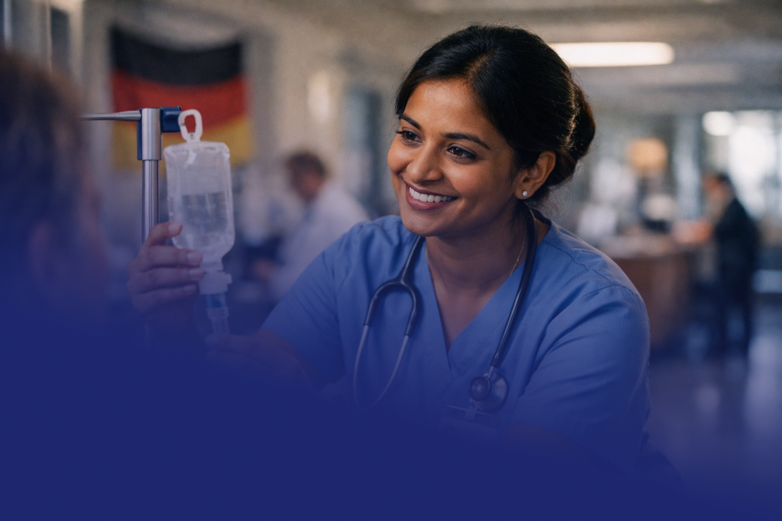 A smiling female healthcare professional in scrubs and a stethoscope, administering IV fluids to a patient in a hospital or clinic setting.