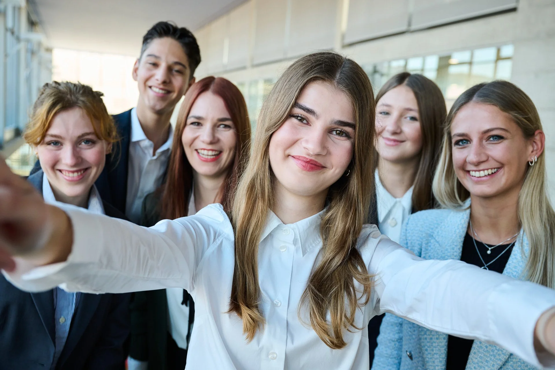 Gruppe junger Menschen macht ein Selfie im Bürogebäude.