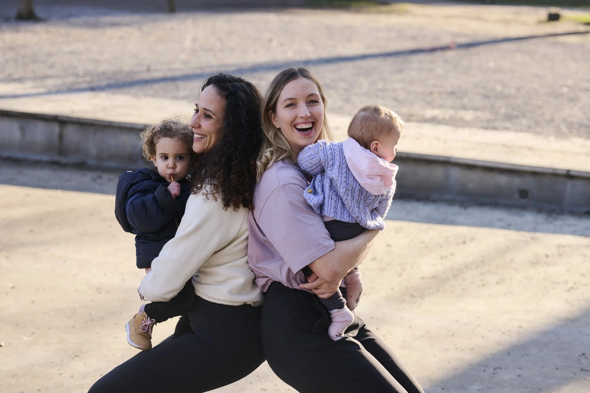 Drei Frauen mit Kindern, lachend auf einem Strand, bei Sonnenuntergang, im Freien