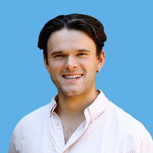 Photo of Dr. William Fleming, with dark hair, wearing a light-colored button-up shirt, smiling against a blue background.