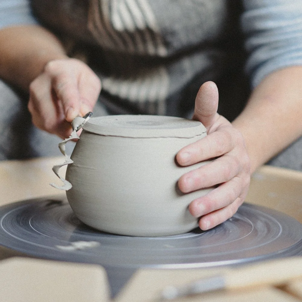 Céramiste façonnant de la poterie sur un tour de potier, en train de donner forme à un bol en argile.