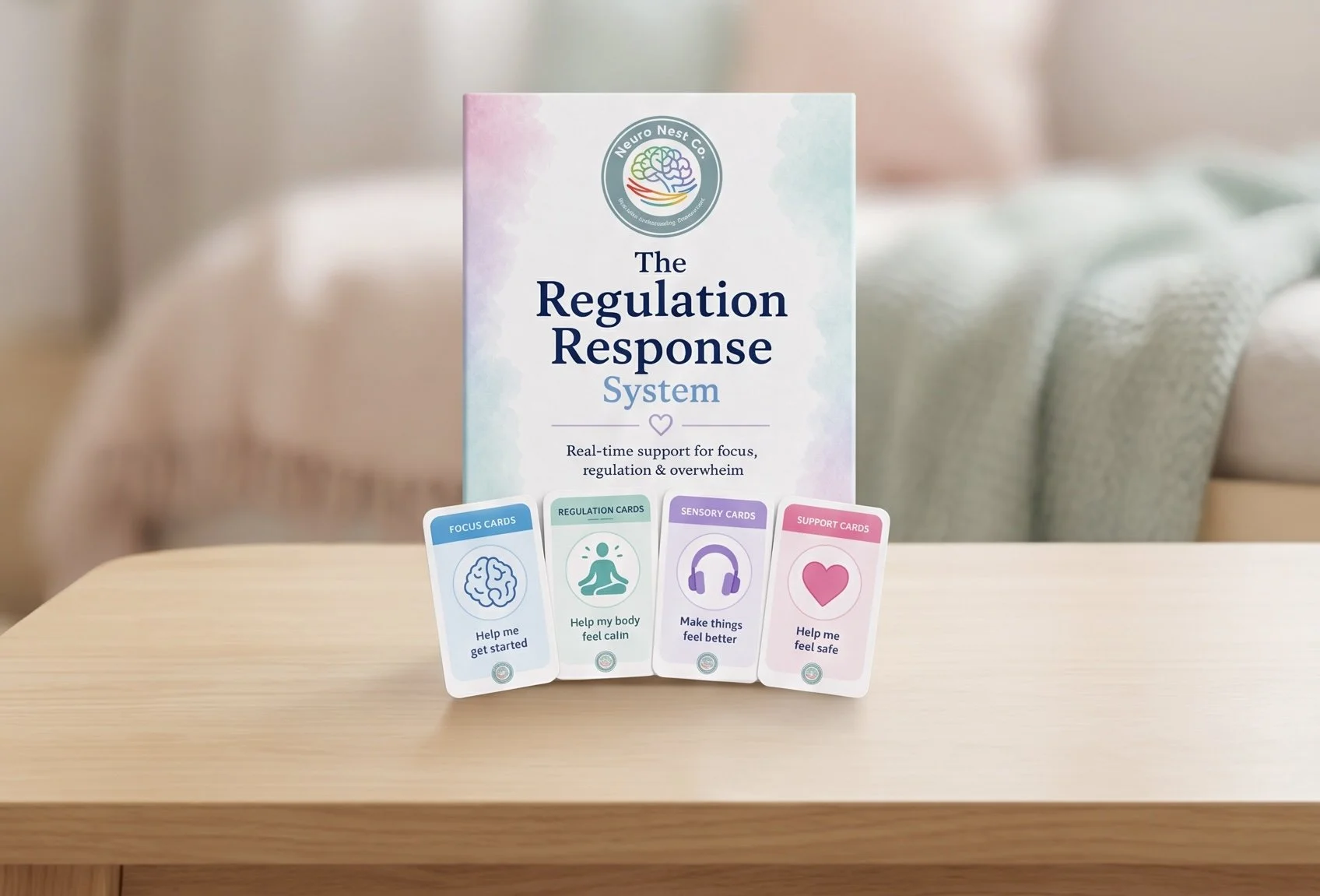 "The Regulation Response System" with four colorful cards in front, each labeled with a different focus: "Help me get started," "Help my body feel calm," "Make things feel better," and "Help me feel safe." The cards are on a wooden surface in front of a book or box with the same title and a logo of a brain surrounded by a circular design, with soft, pastel watercolor-like background.