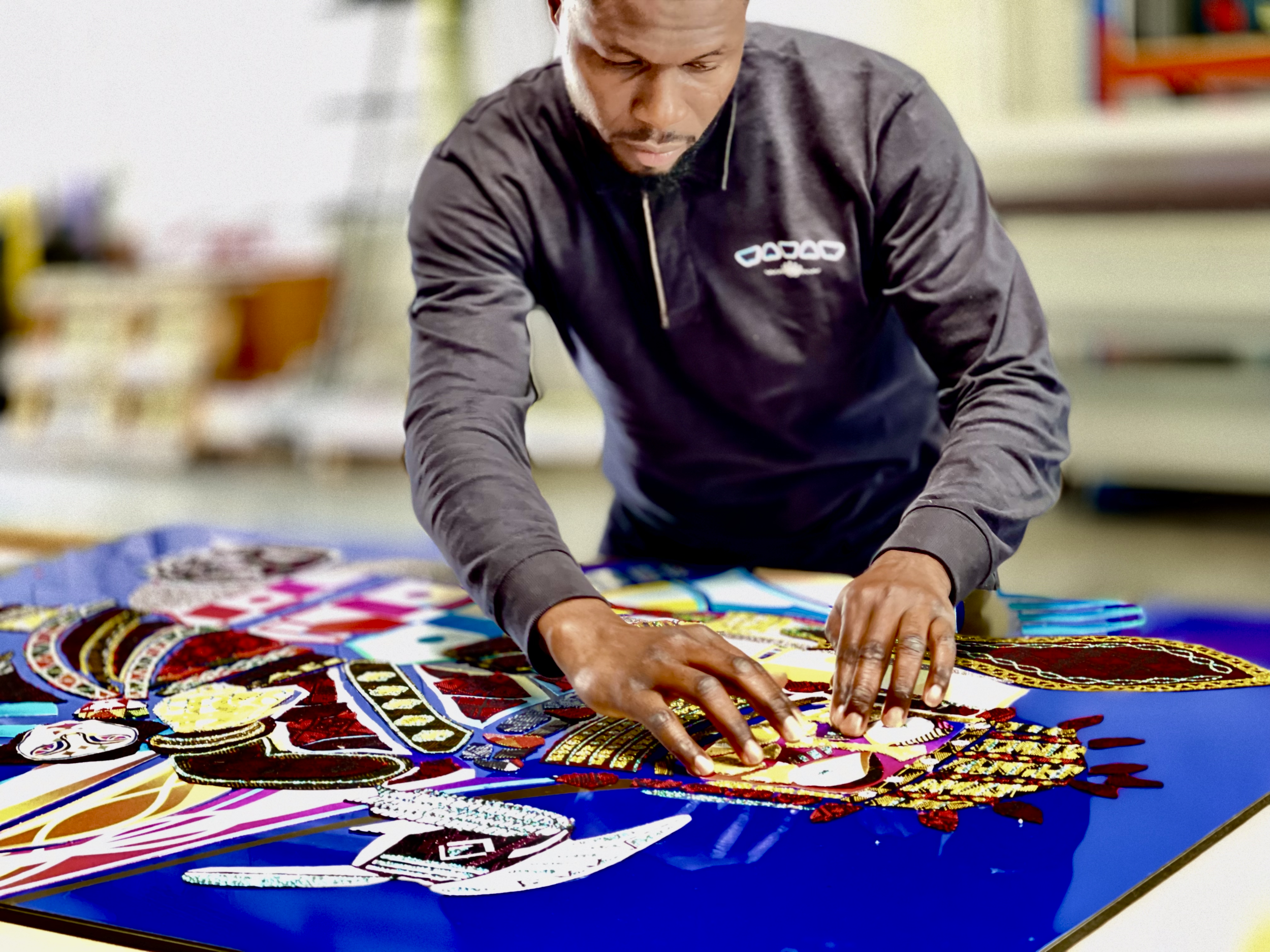 L'artiste plasticien Afa Faty dans son atelier en train d'oeuvrer un tableau d'art contemporain avec des étoffes tissées d'Afrique réalisées par les différents maîtres tisserands,