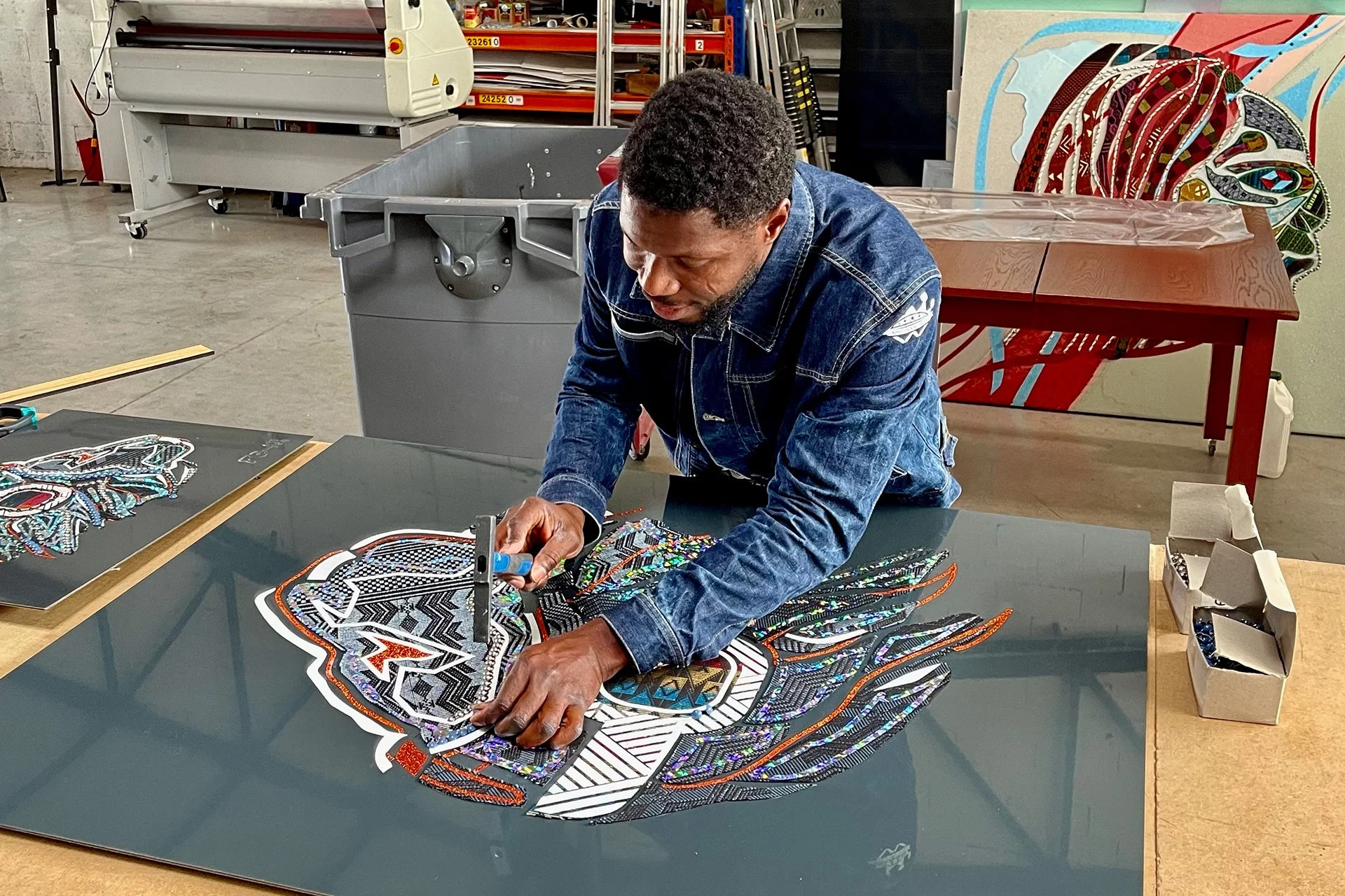 Afa Faty dans son atelier à Thiès - Artiste plasticien et designer graphic en pleine création d'une œuvre Art for Artefacts. Détail du cloutage sur étoffe tissée et conception numérique Full HD.