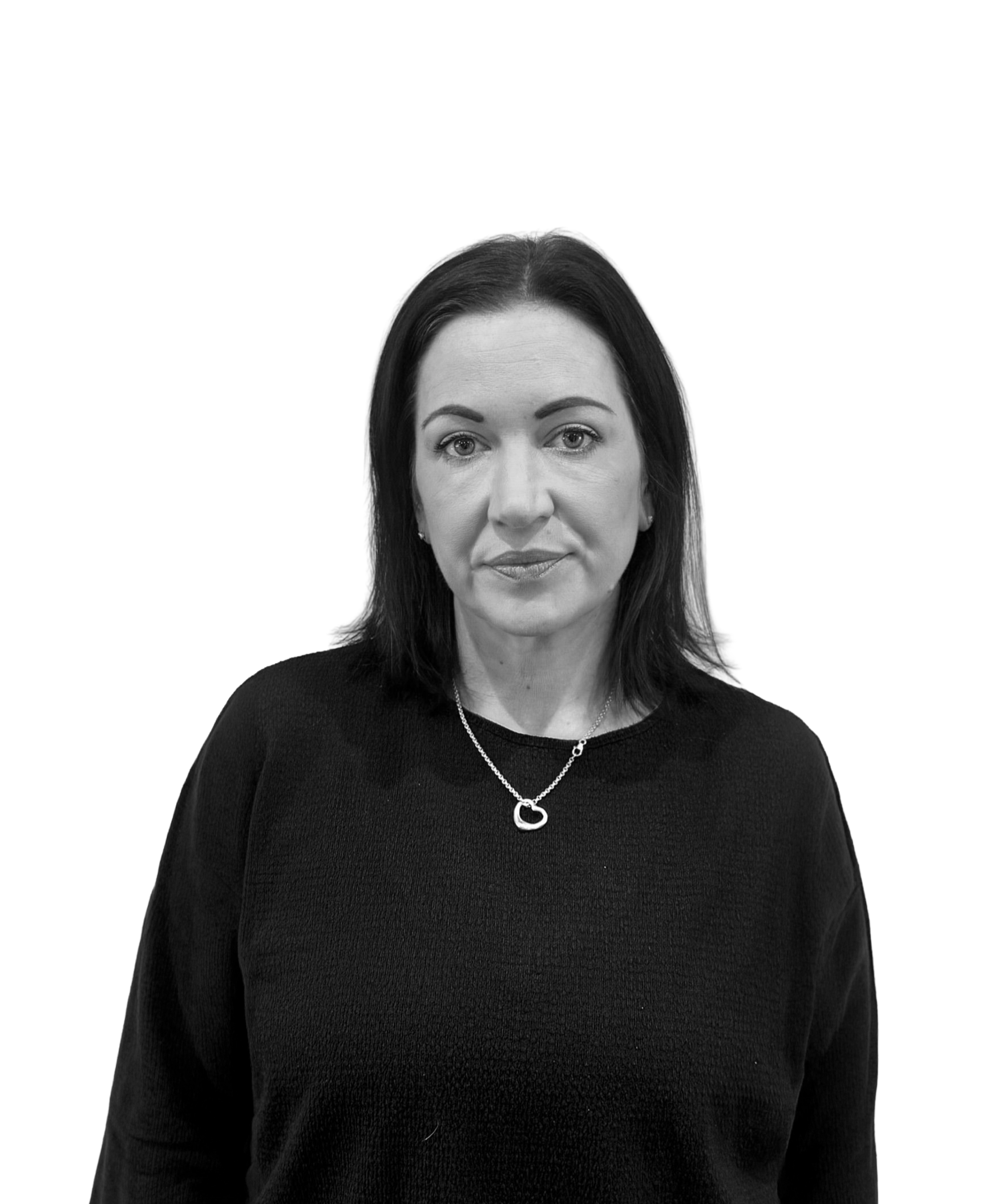 Black and white photo of a woman with dark hair, wearing a black top and a heart-shaped pendant necklace, against a plain white background.