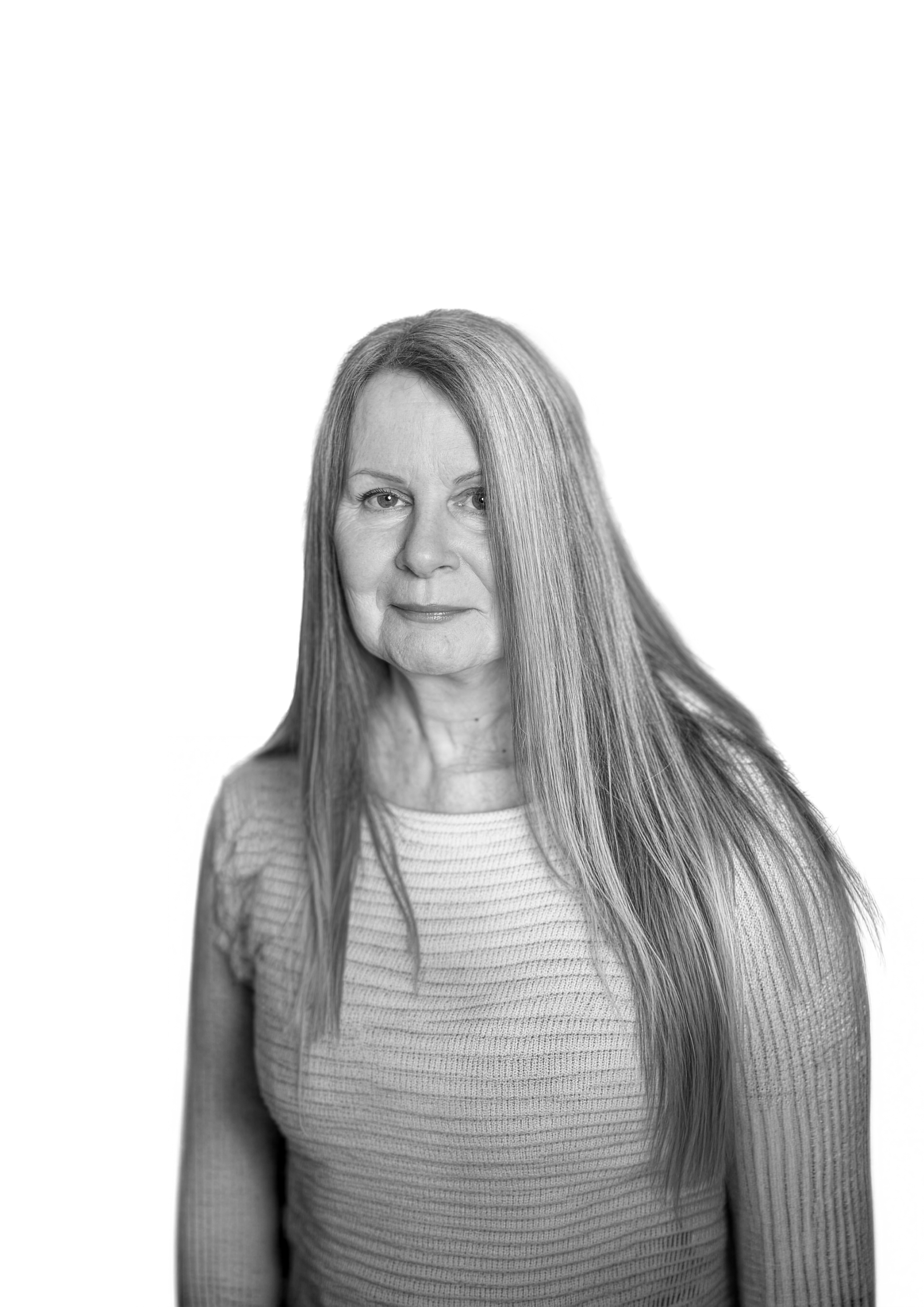 Black-and-white portrait of a woman with long straight hair, wearing a textured top, looking directly at the camera with a neutral expression.