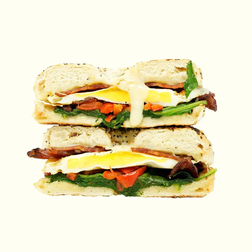 Early Bird Bagel - Two poached eggs, bacon, spinach, red pepper, pepperjack cheese on an everything bagel. Contains Gluten