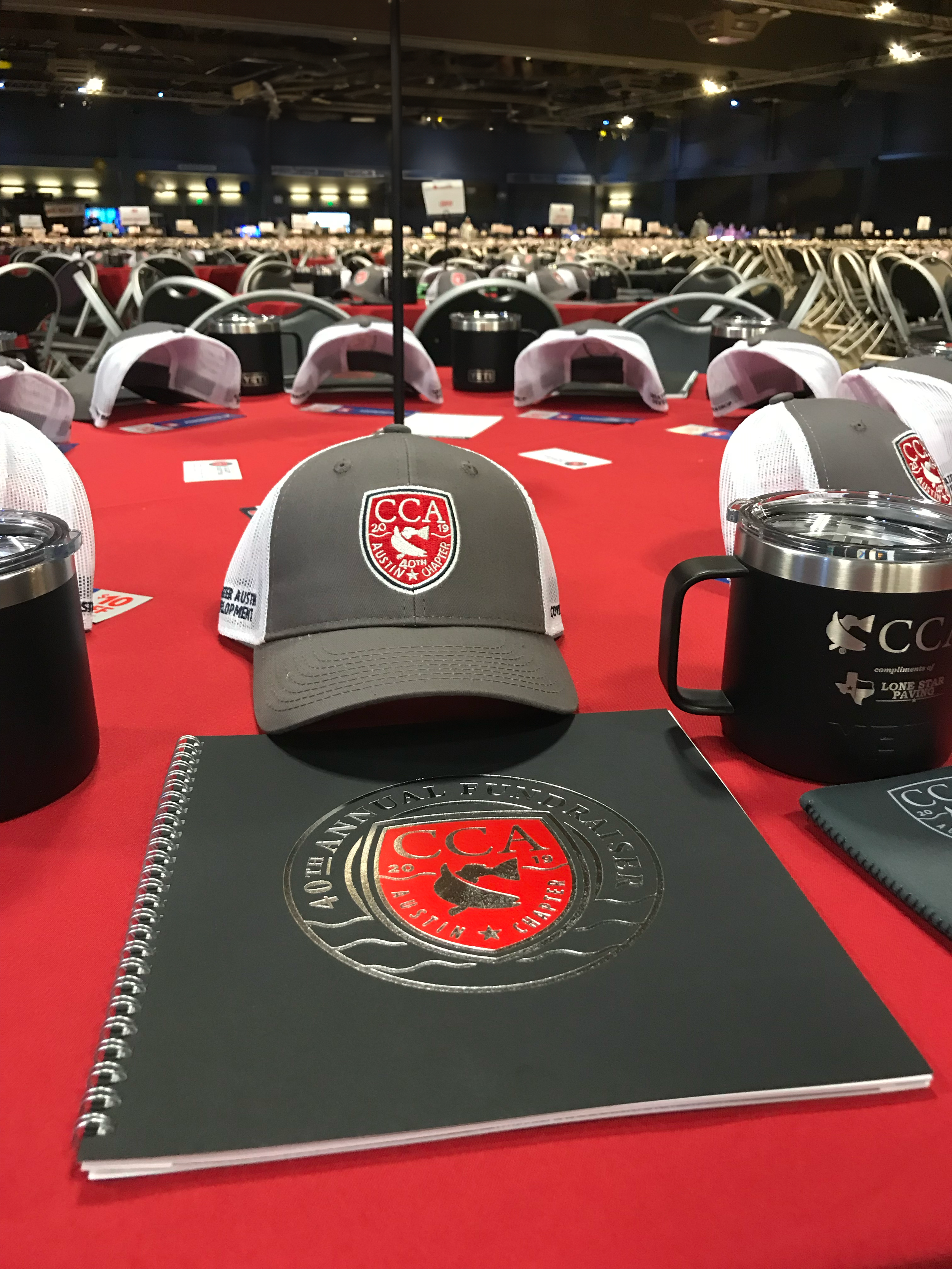 Each guest receives a program, hat, koozie, and table gift (typically a YETI product).