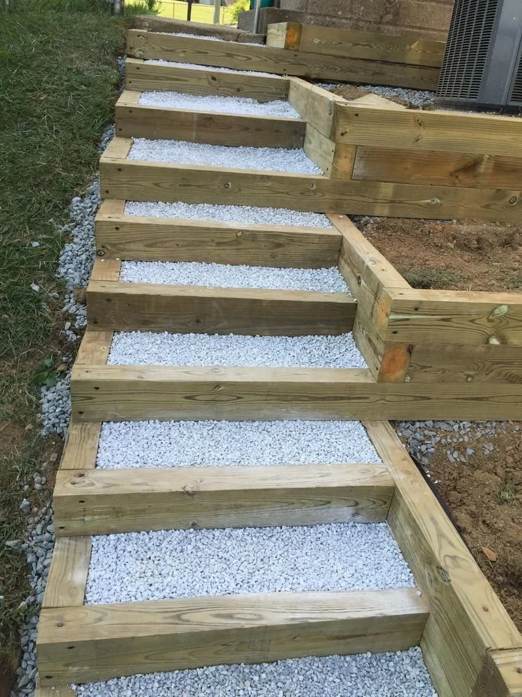 Escaliers en bois avec une base de gravier blanc, construction en cours pour une allée ou un escalier extérieur.