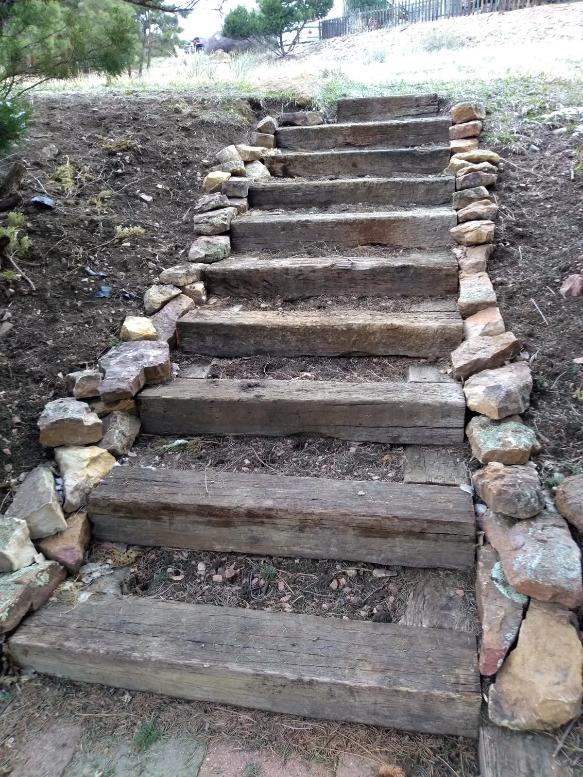 Escalier en bois avec des pierres de chaque côté dans un environnement naturel.