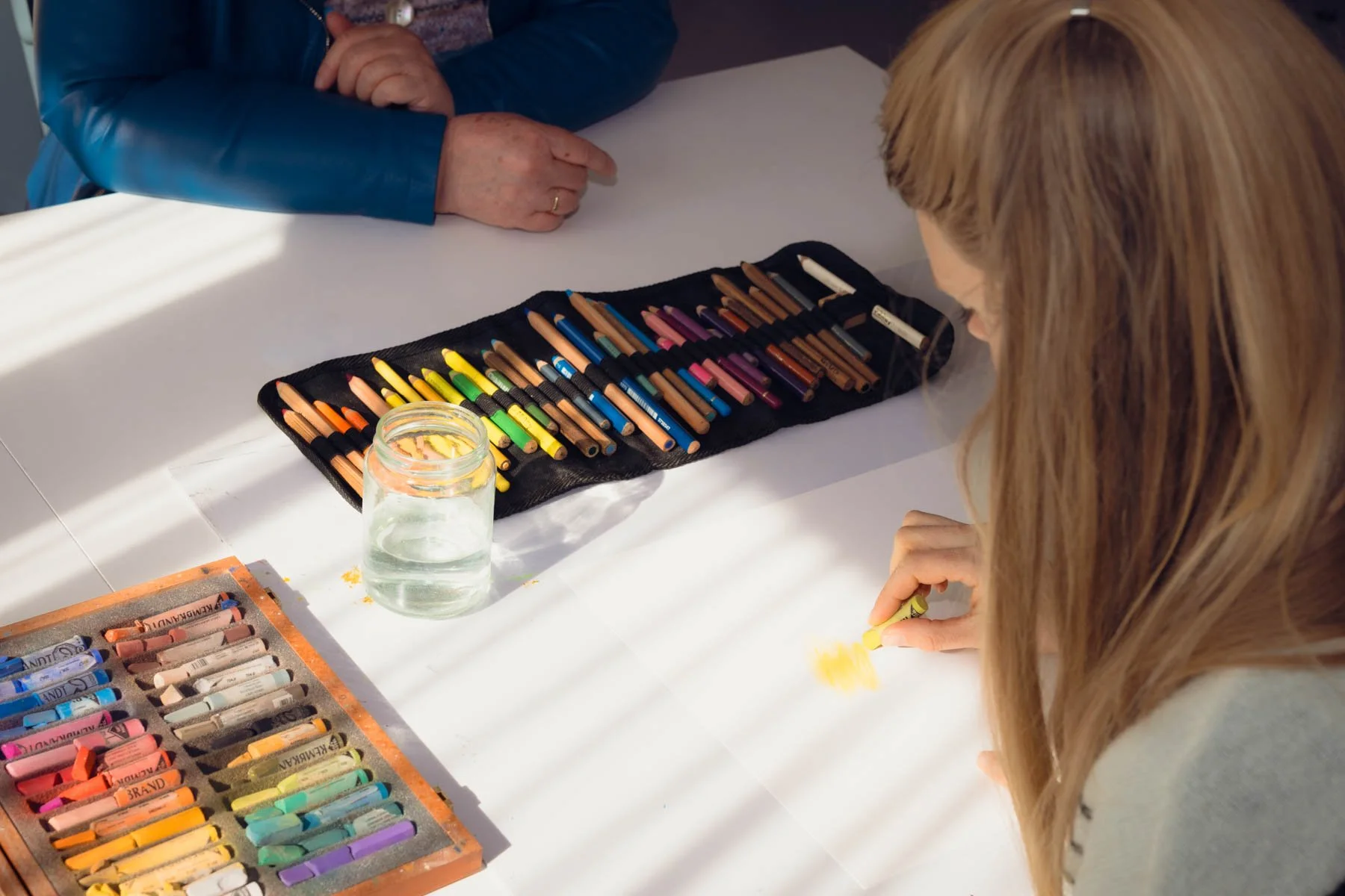 Cliënt tekent met pastelkrijt terwijl Karin Boodt begeleidt.