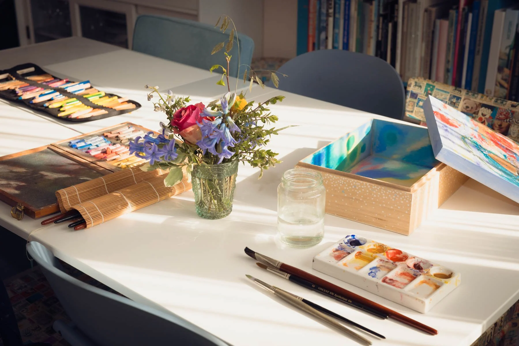 De keukentafel van Karin Boodt met creatieve materialen, koesterkist en bloemen.