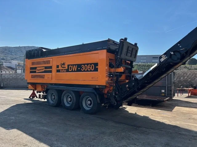 Une machine de construction orange avec un bras élévateur dans un espace extérieur.