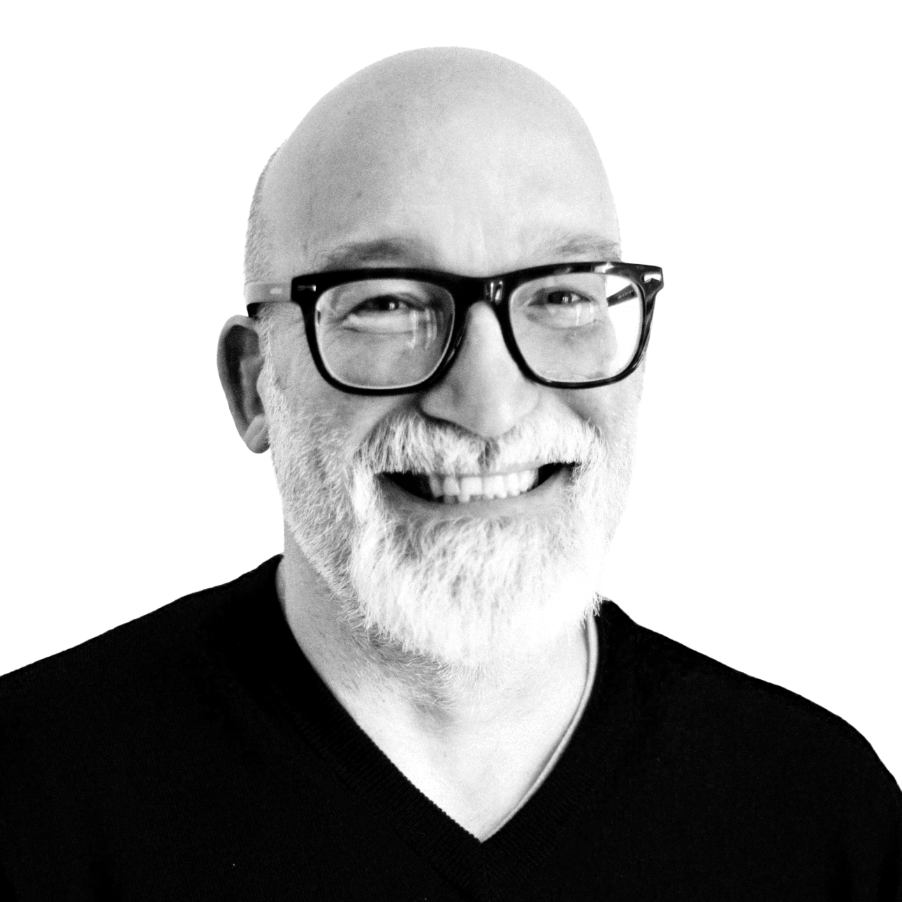 Black and white portrait of a smiling older man with glasses, white beard, and mustache, wearing a black shirt, against a background divided into black and white.