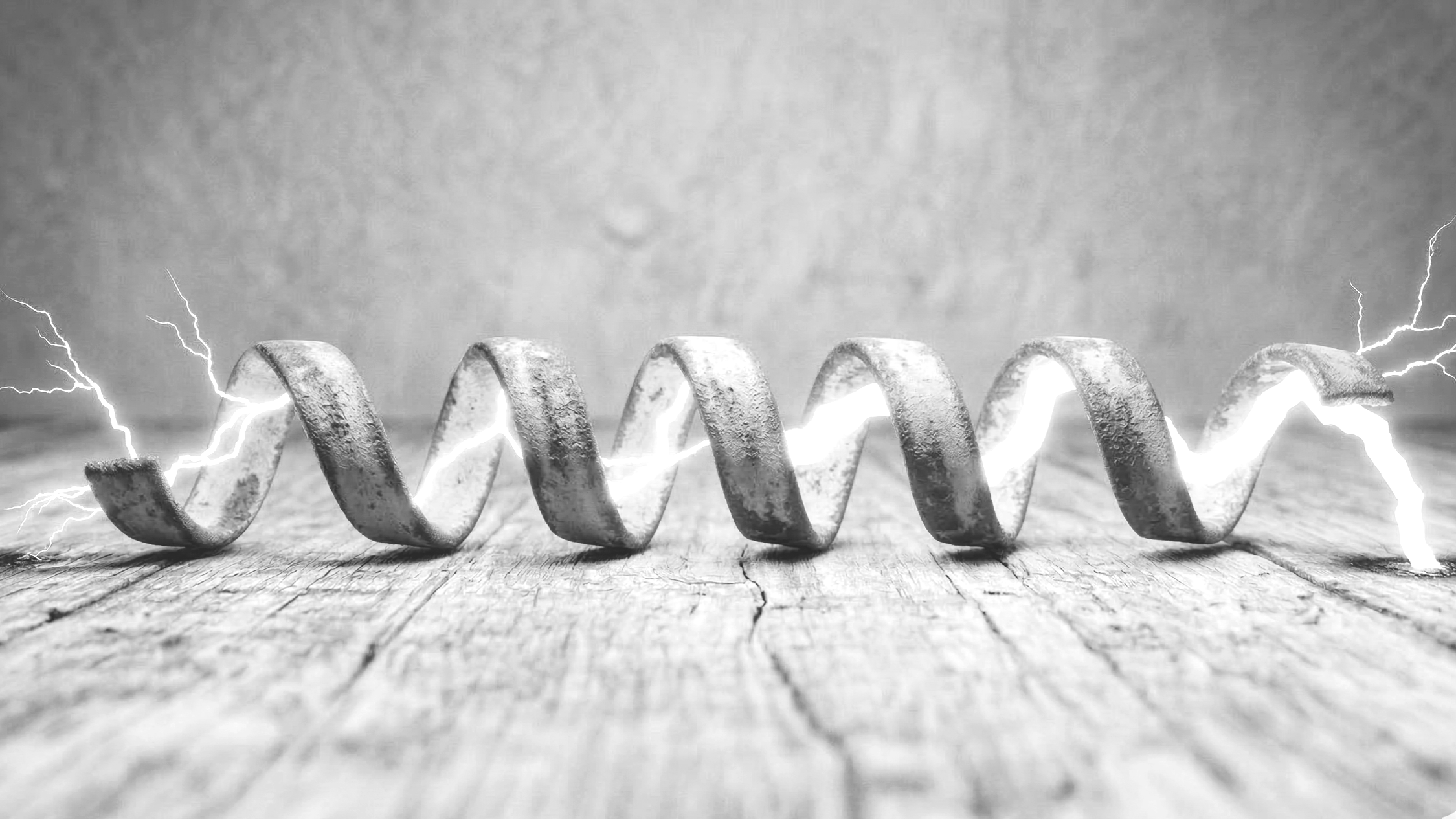 A metal coil on a wooden surface with visible cracks, surrounded by electrical sparks and lightning in a black and white photograph.