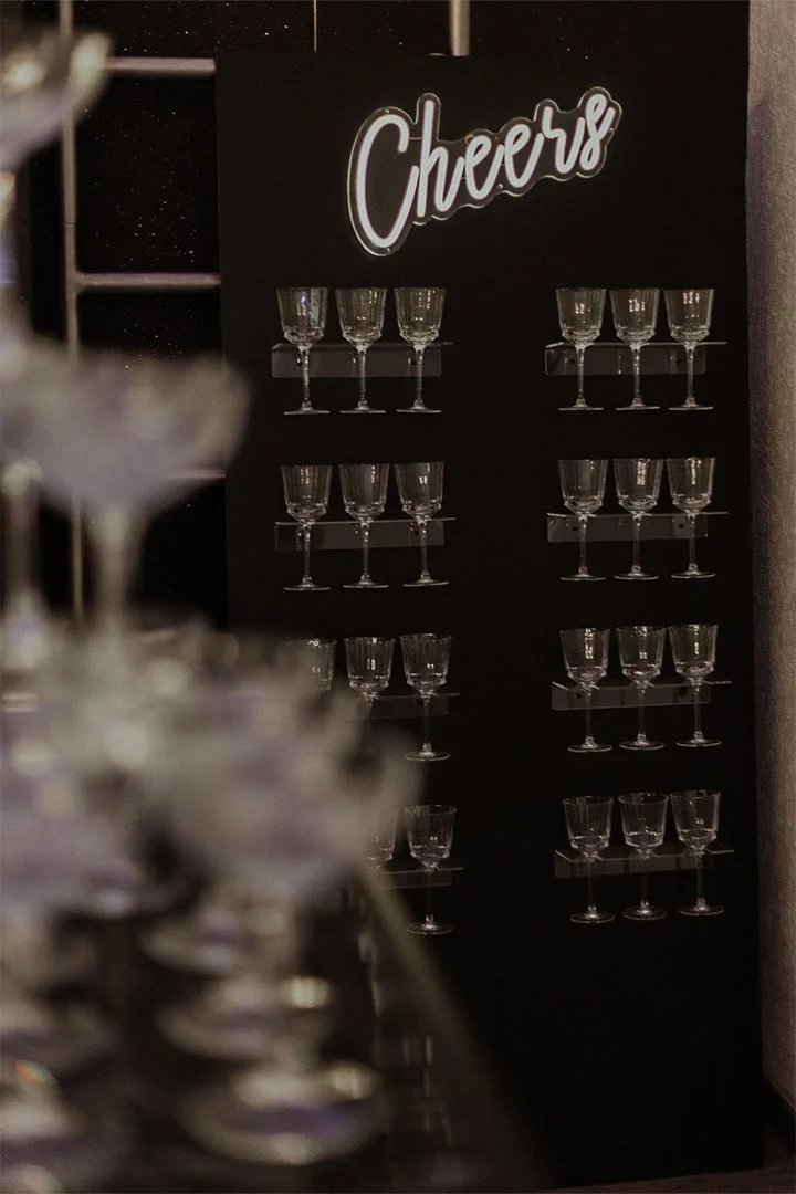 Sektgläser sind auf einem schwarzen Schild mit der Aufschrift "Cheers" platziert.