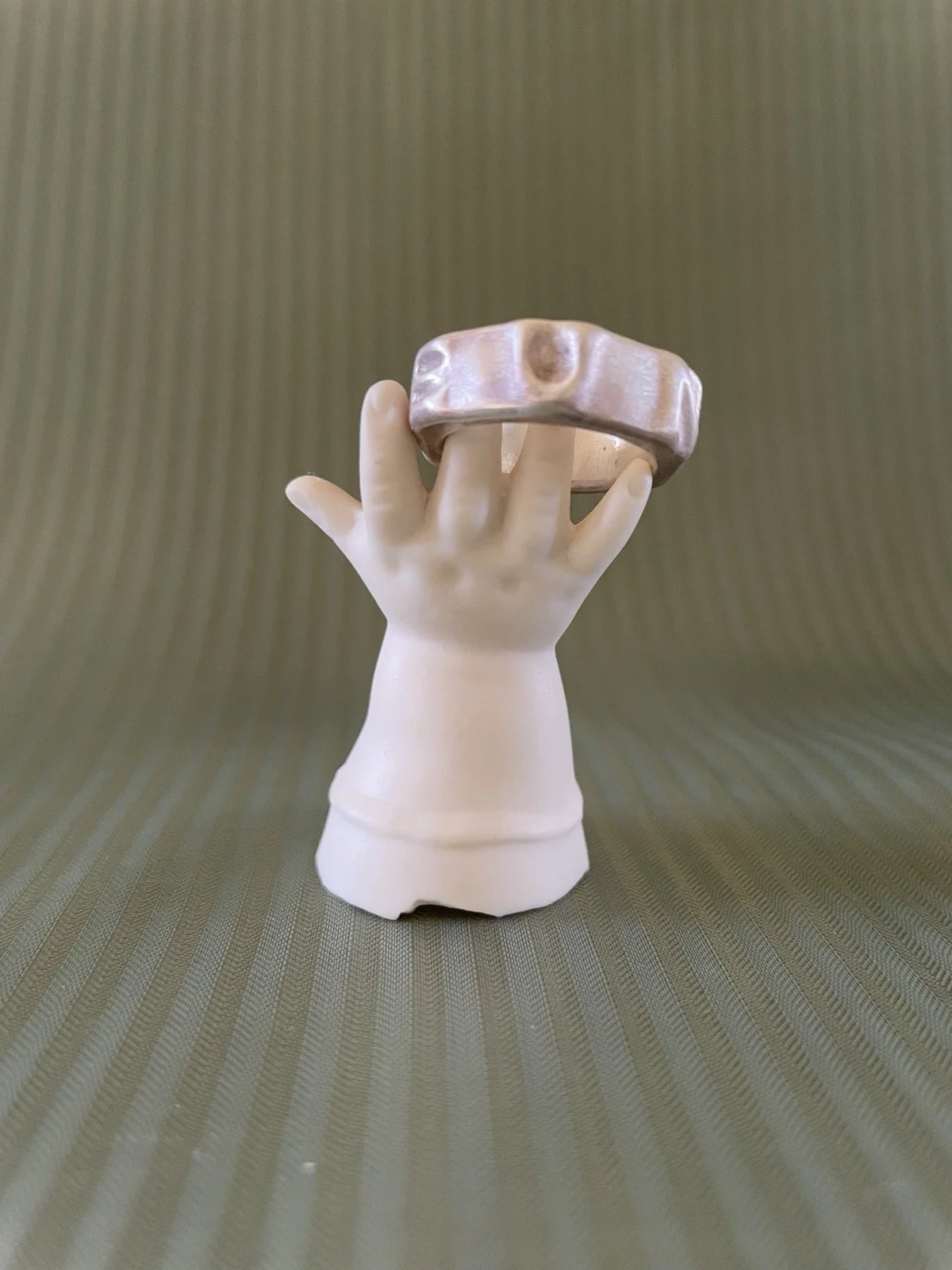 Ring auf einem dekorativen Ständer in Form einer Puppenhand aus weißem Porzellan.