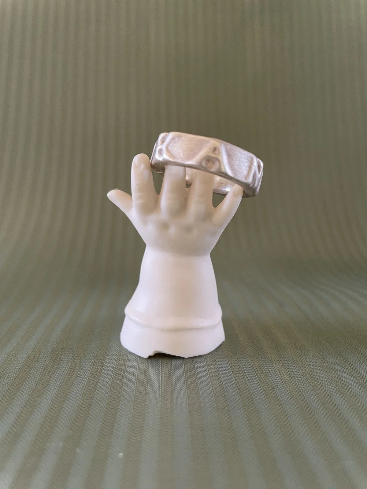 Ring auf einem dekorativen Ständer in Form einer Puppenhand aus weißem Porzellan.