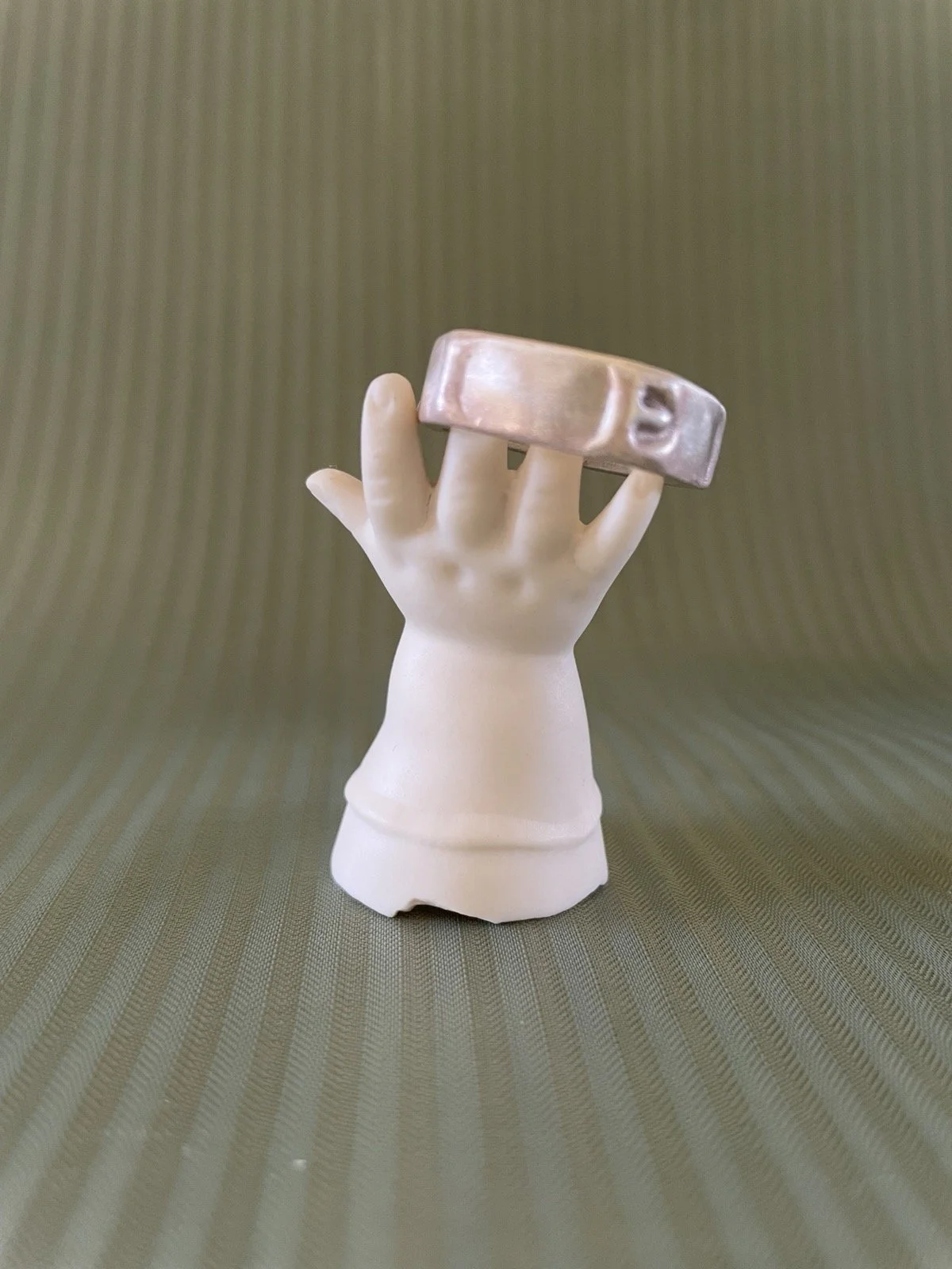 Ring auf einem dekorativen Ständer in Form einer Puppenhand aus weißem Porzellan.
