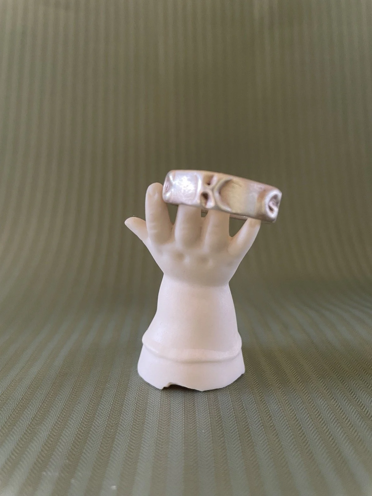 Ring auf einem dekorativen Ständer in Form einer Puppenhand aus weißem Porzellan.