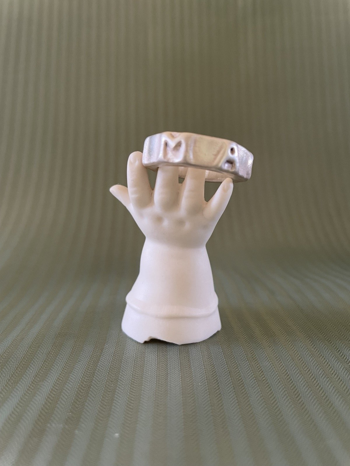 Ring auf einem dekorativen Ständer in Form einer Puppenhand aus weißem Porzellan.