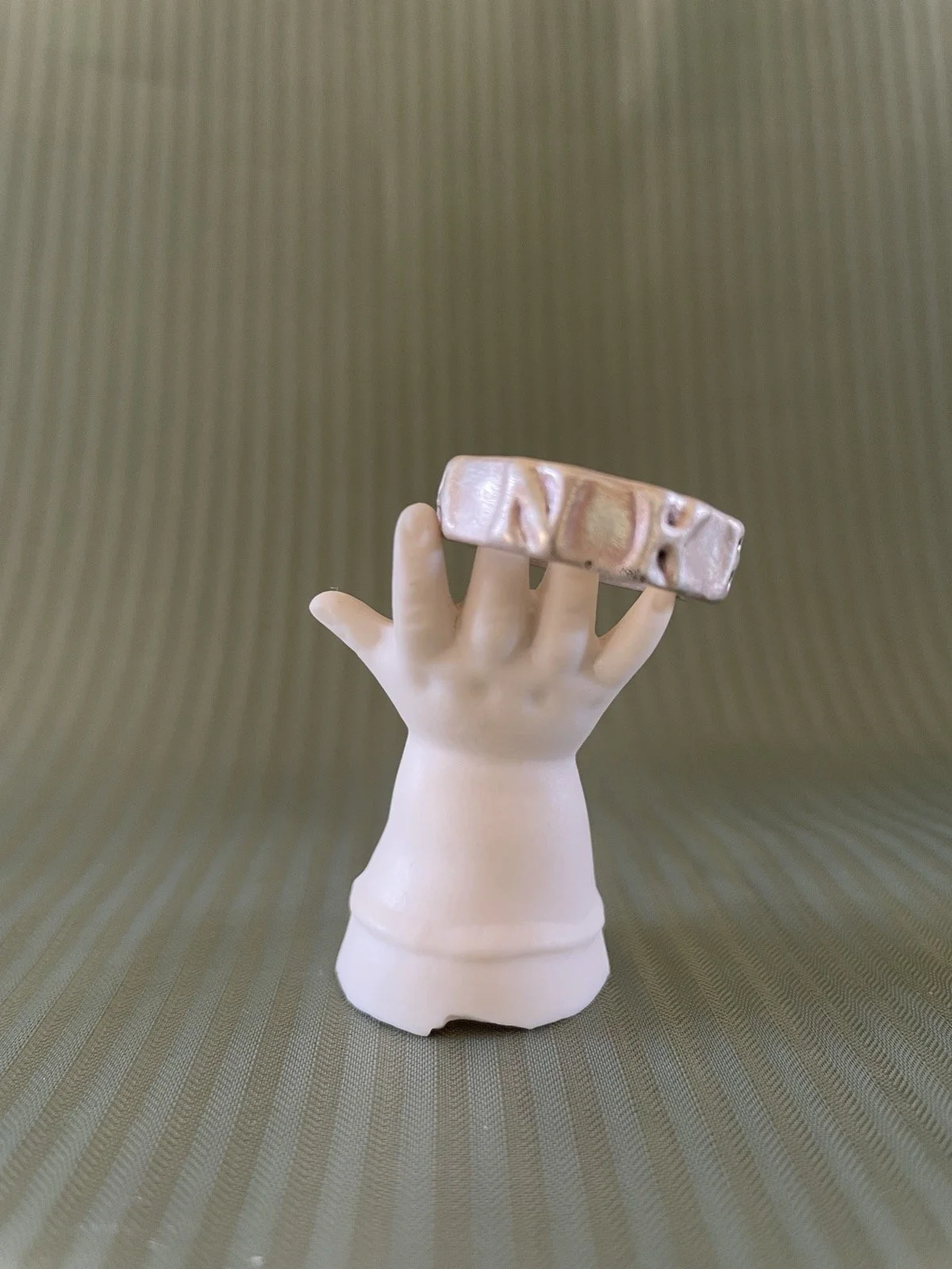 Ring auf einem dekorativen Ständer in Form einer Puppenhand aus weißem Porzellan.