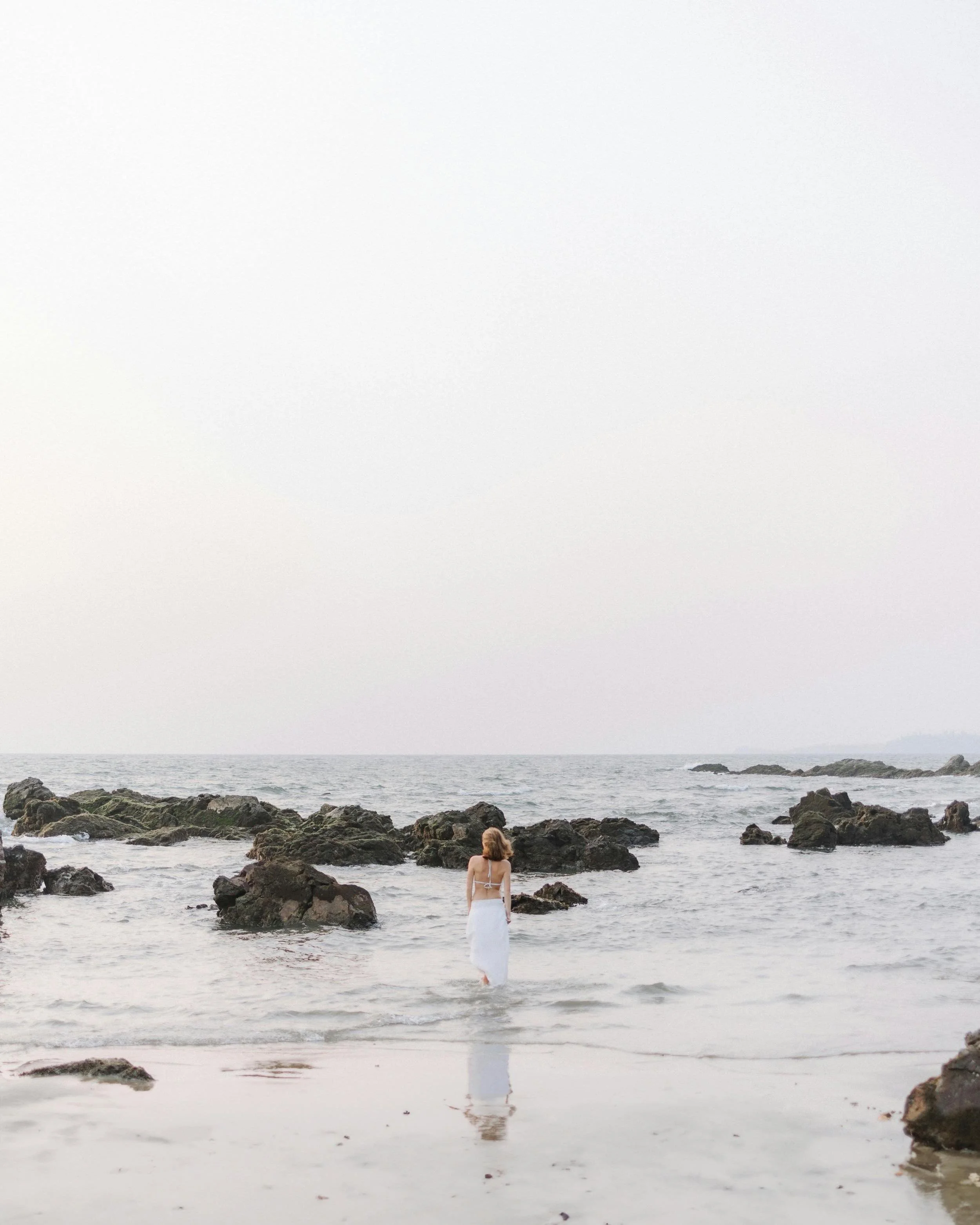 Young woman while walking on a beach, diving her feet into the ocean.