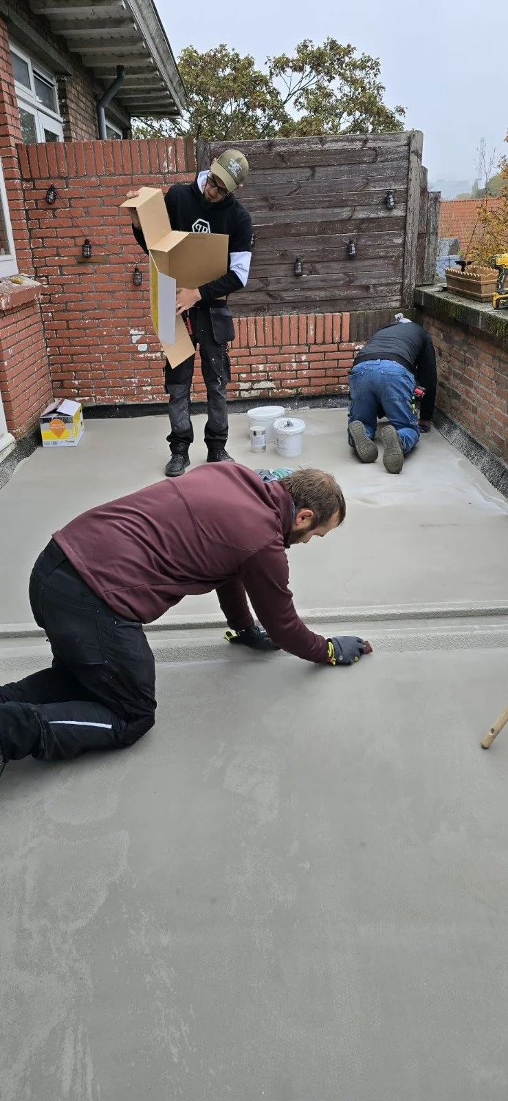 Mensen leggen een betonnen vloer in een buitenruimte aan.