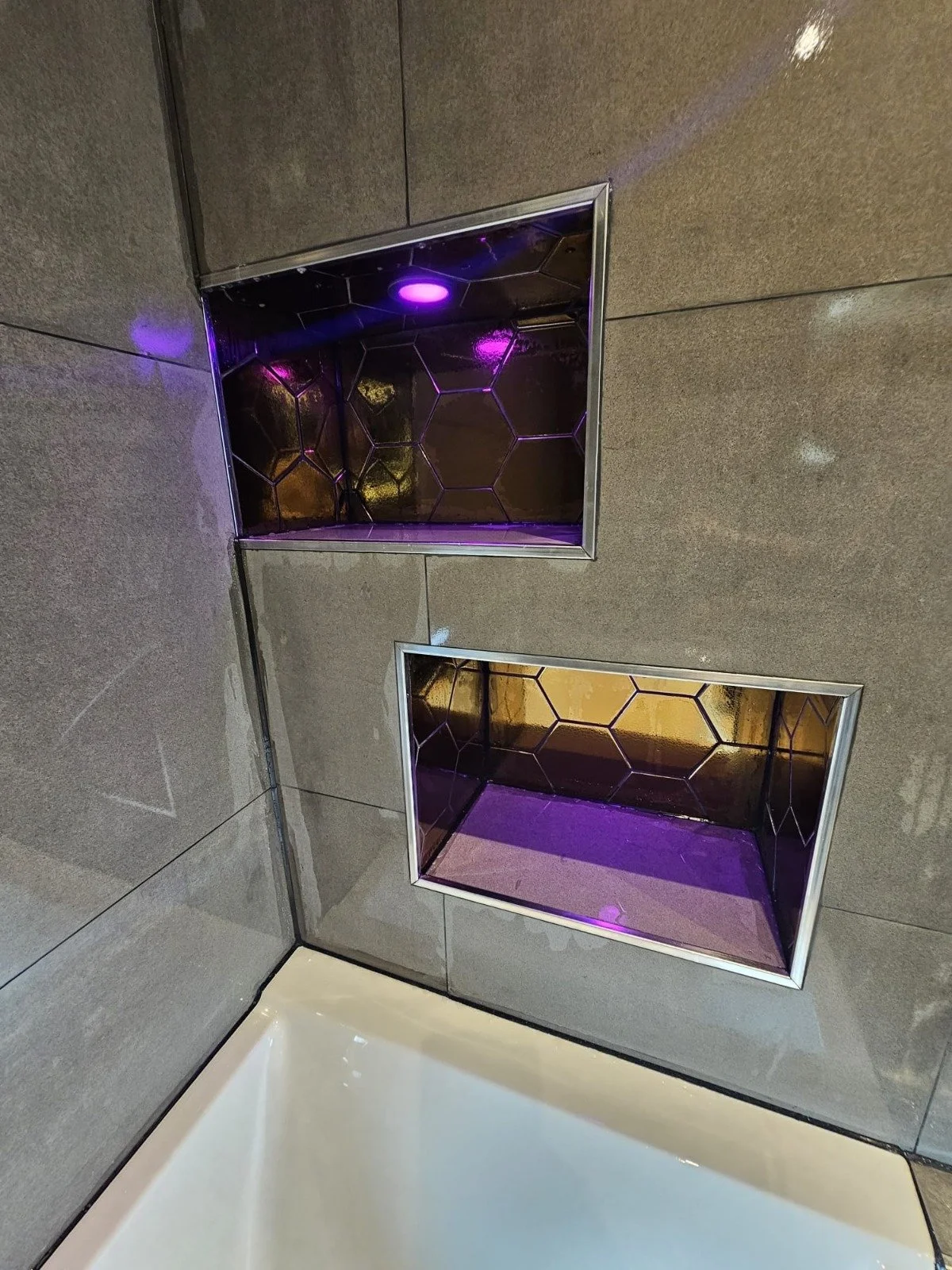 Namen van de twee niches in de muur met hexagonale glasdeksels en paarse verlichting