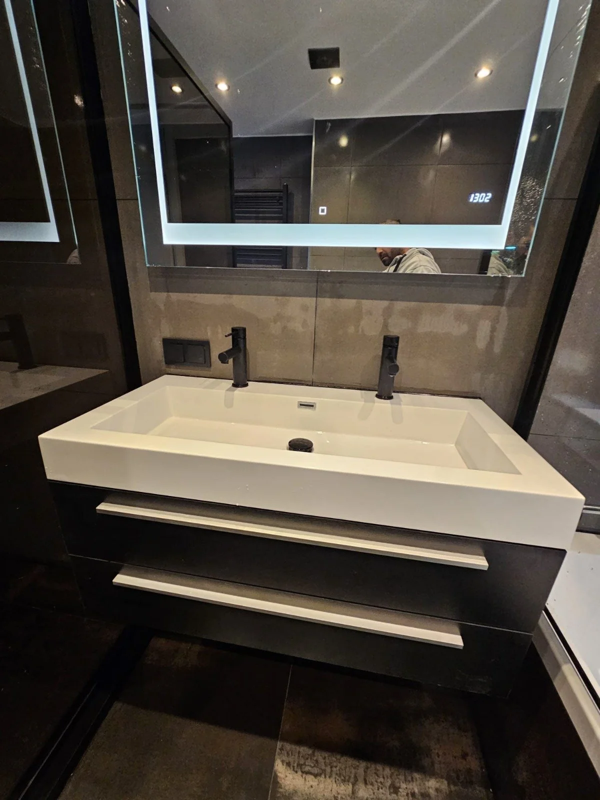 Moderne badkamer met dubbele wasbak, grote spiegel en zwarte kranen.