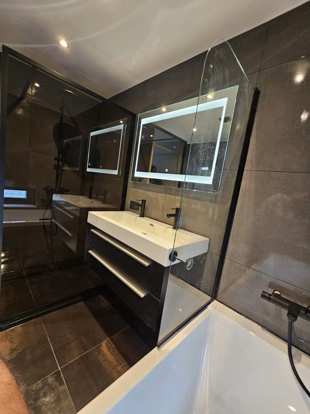 Moderne badkamer met dubbele wastafel, spiegel met verlichting, inloopdouche en bad.