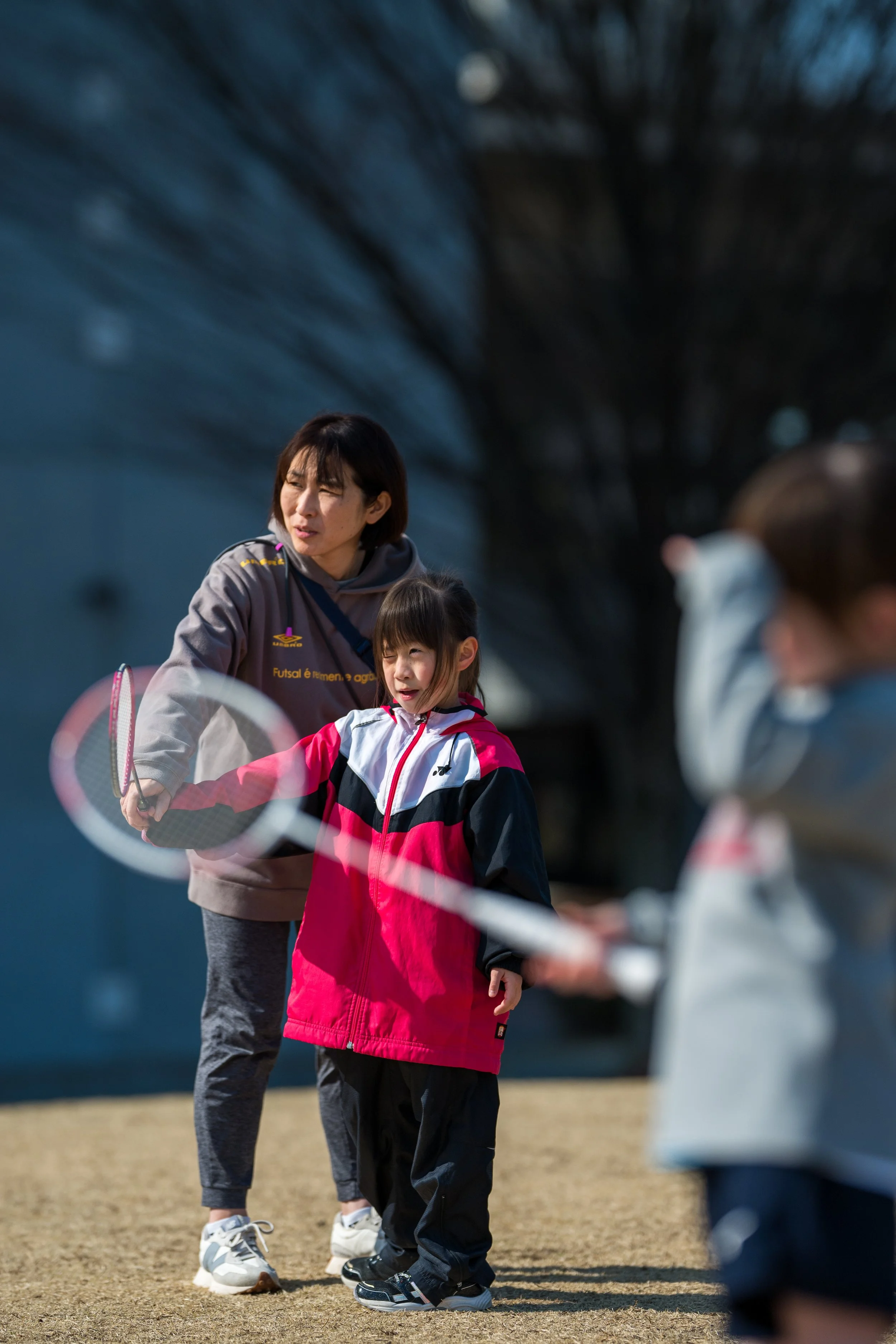子供と女性がテニスの練習をしている様子。
