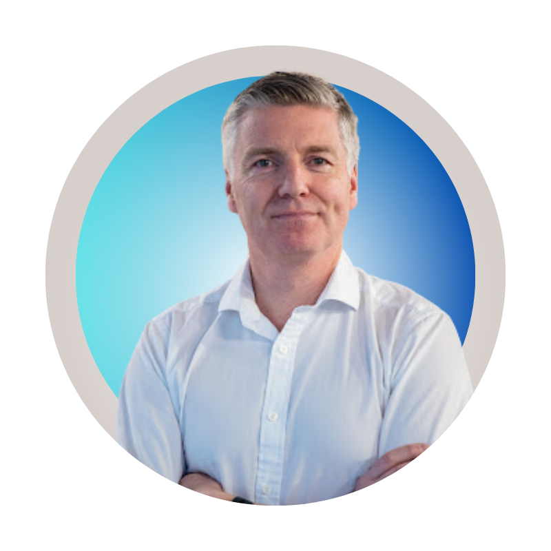 A middle-aged man in a white button-up shirt stands with his arms crossed, against a blue gradient background inside a circular frame.