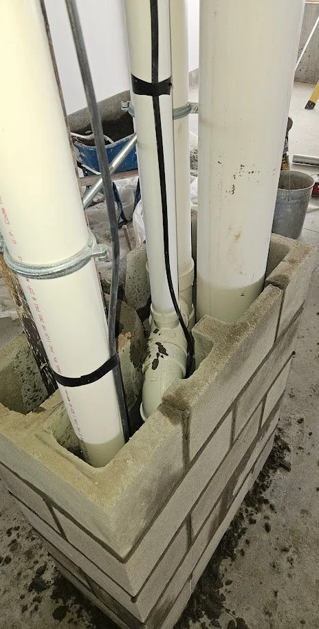 underground plumbing pipes within a concrete block wall