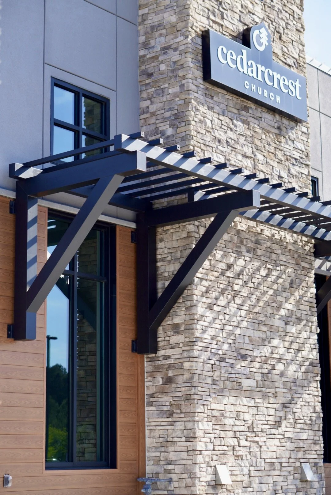Exterior of Cedarcrest Church building with stone and wood siding, large windows, and a metal awning.