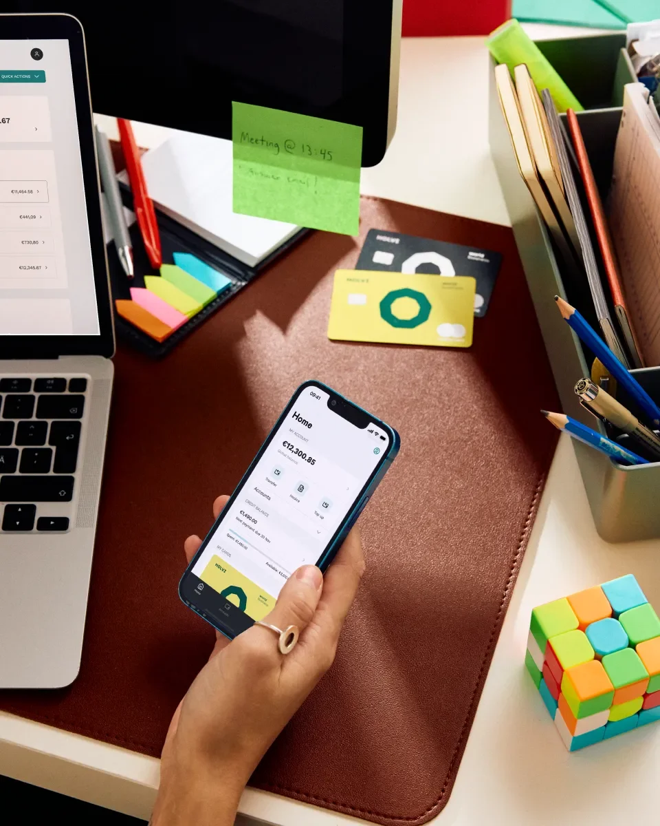 Kuva puhelimesta toimiston pöydällä. Puhelimen näytöllä näkyy Holvin mobiilisovellus.