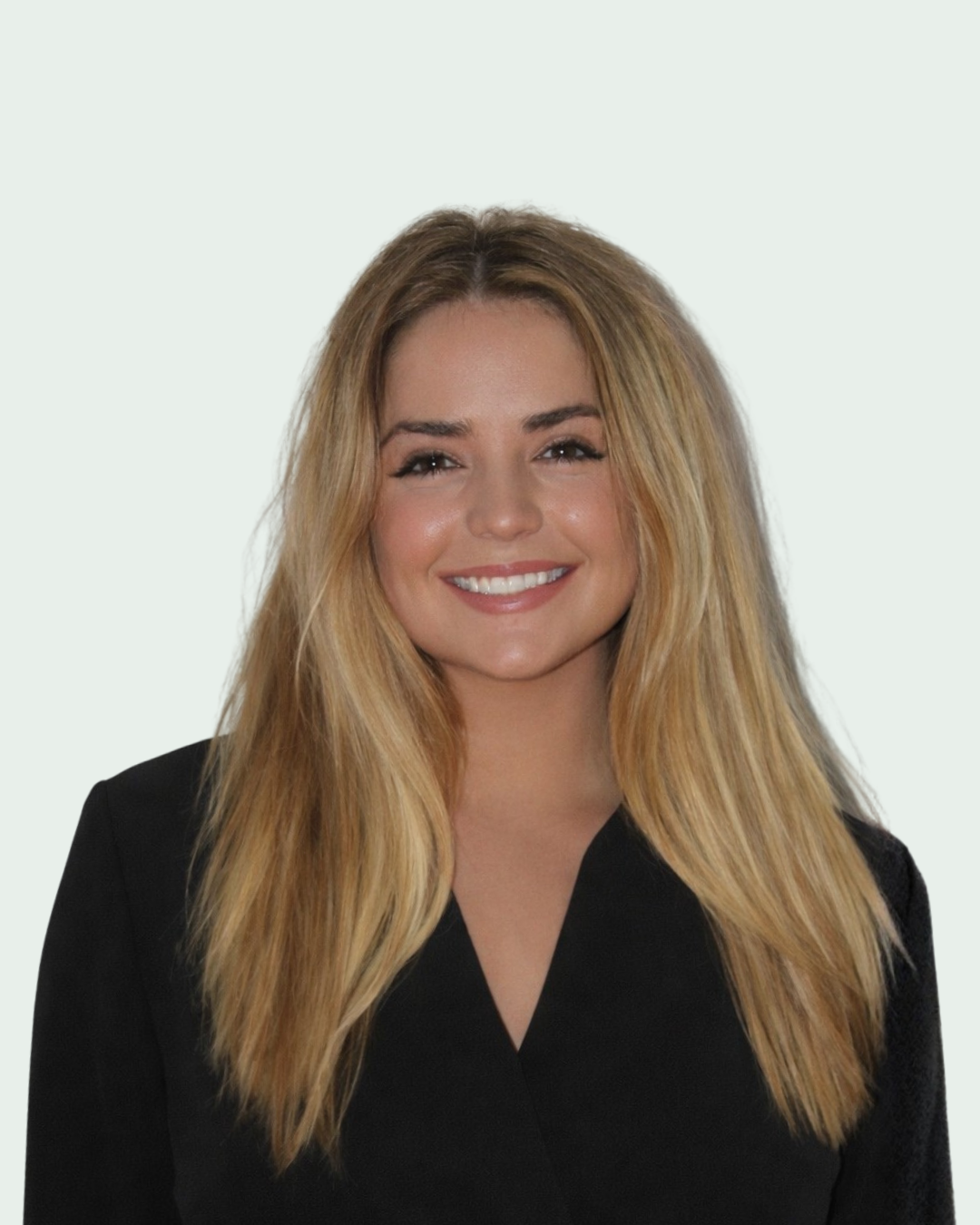 A woman with long blonde hair smiling at the camera, wearing a black top, against a plain light background.