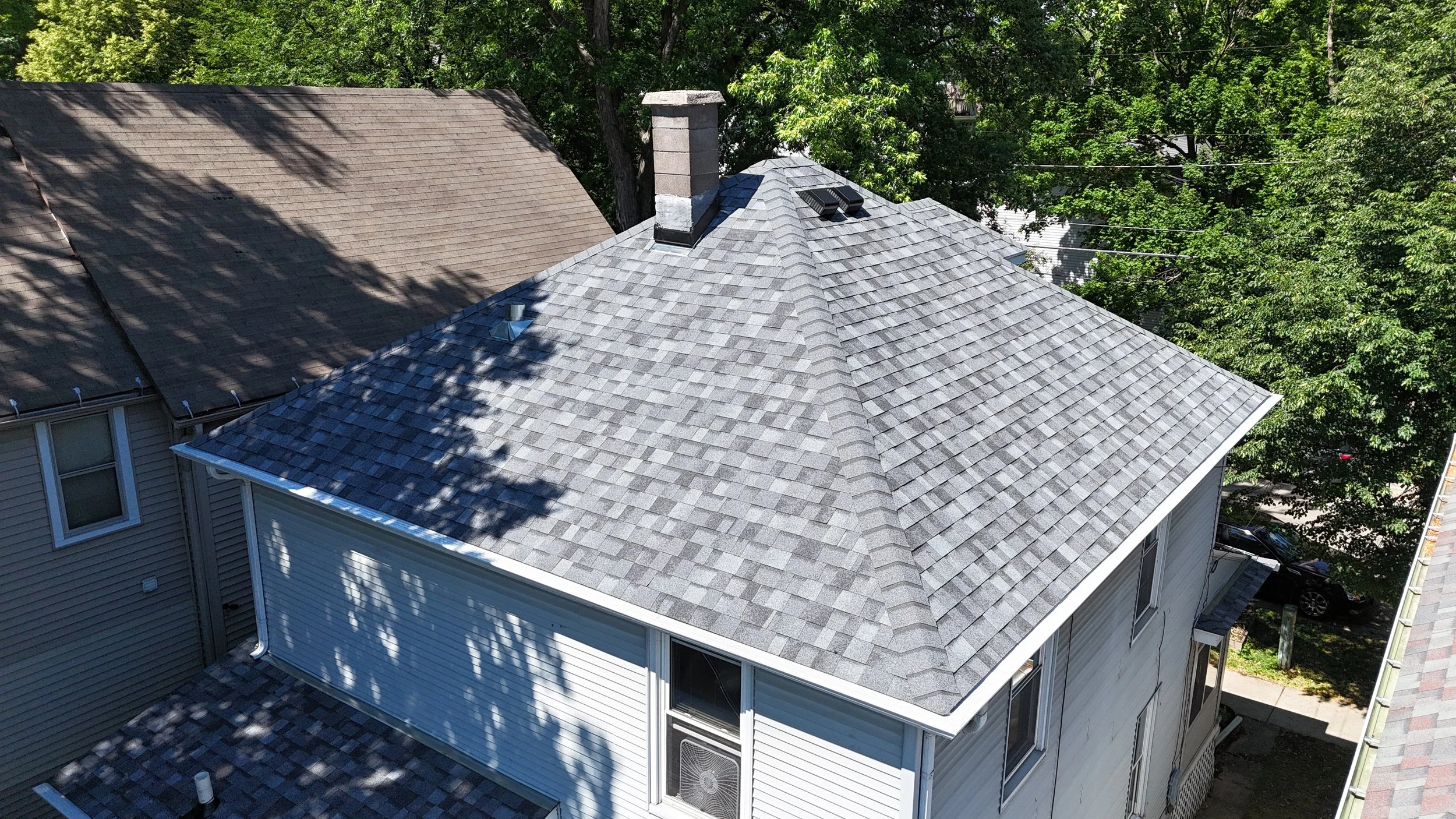 Close aerial view of a residential roof with Owens Corning Duration Slatestone Gray shingles and chimney.