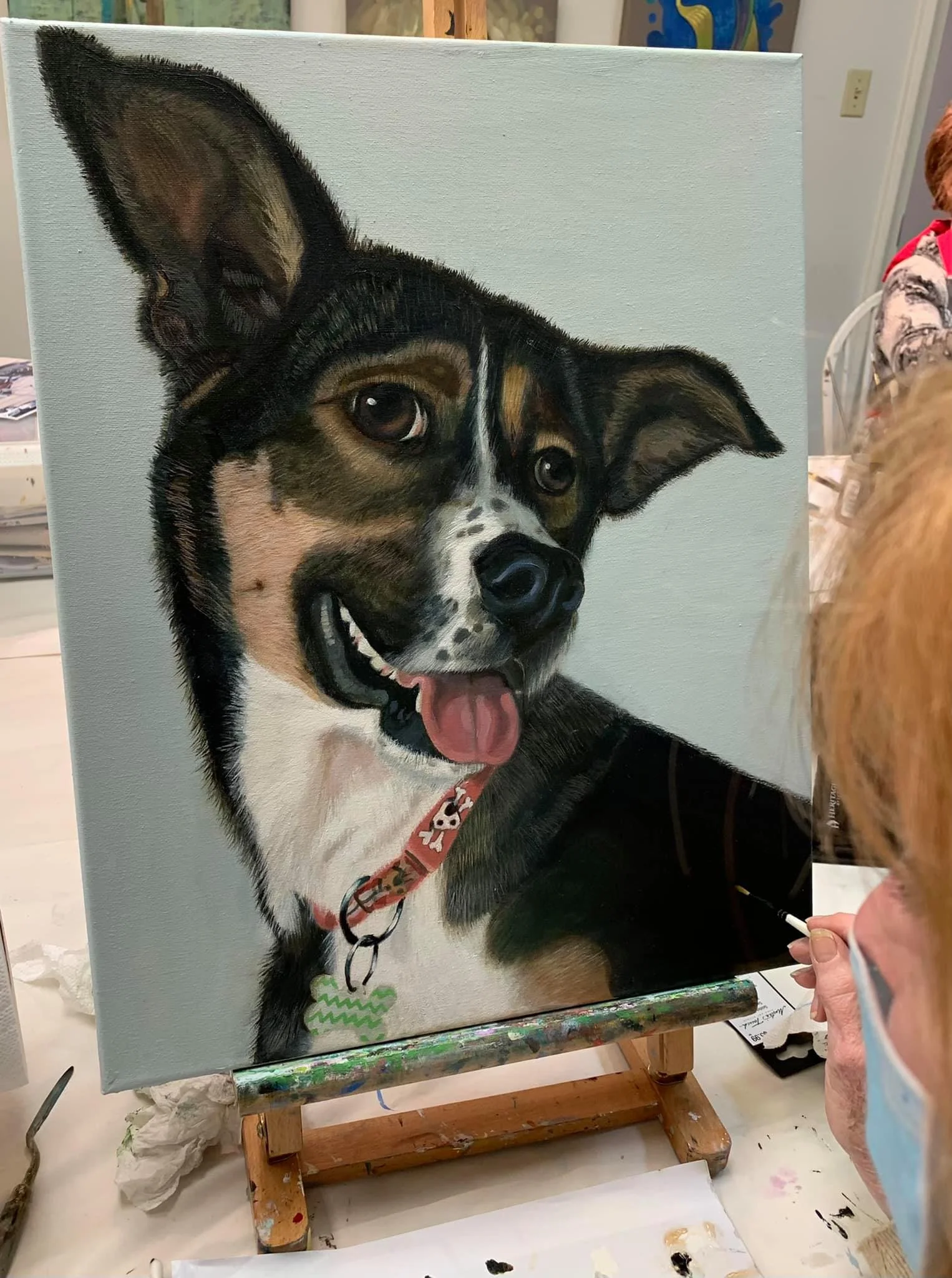 A realistic painting of a happy dog with black, brown, and white fur, wearing a red collar with a white pattern. The dog is looking slightly to the side with its tongue sticking out.