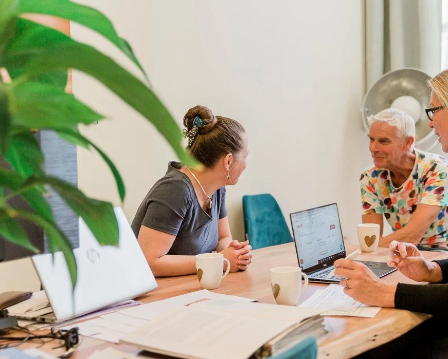 Deur met de tekst 'Sellia's Powerroom', binnen een vergaderruimte met mensen die werken op laptops en een grote groene plant.