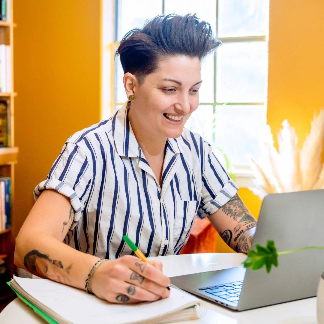 A person on their laptop at a desk, engaged in an online therapy session.