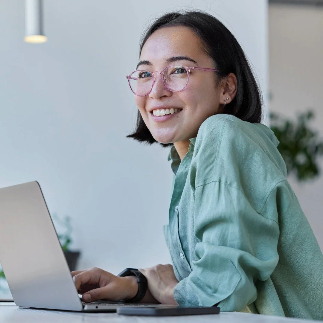 A person on a laptop in a bright, modern office space engaged in an online therapy session.
