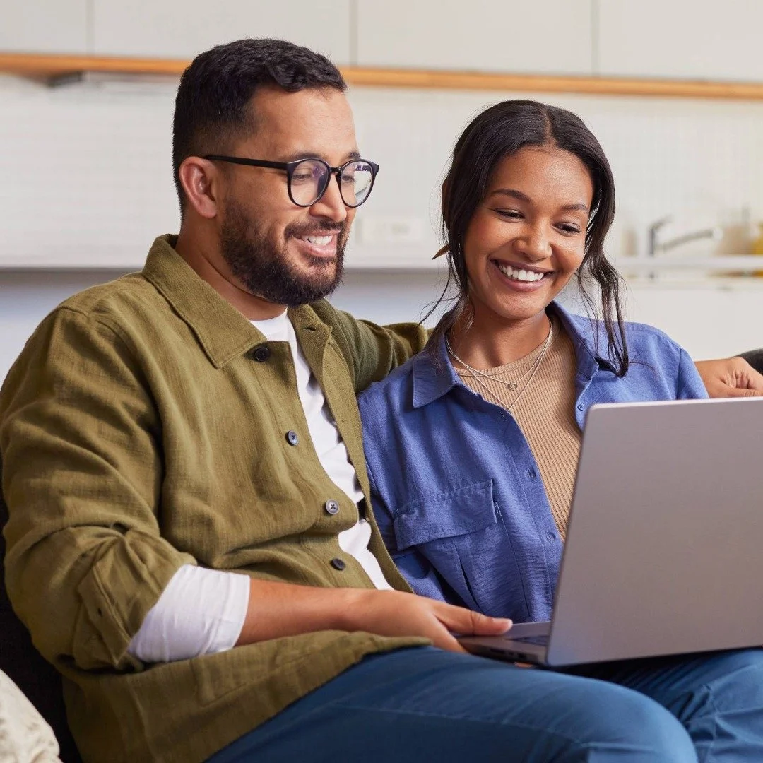 A couple sitting next to each other, engaged in online therapy together.