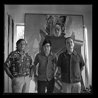 Three men standing in front of a large portrait painting in an art gallery.