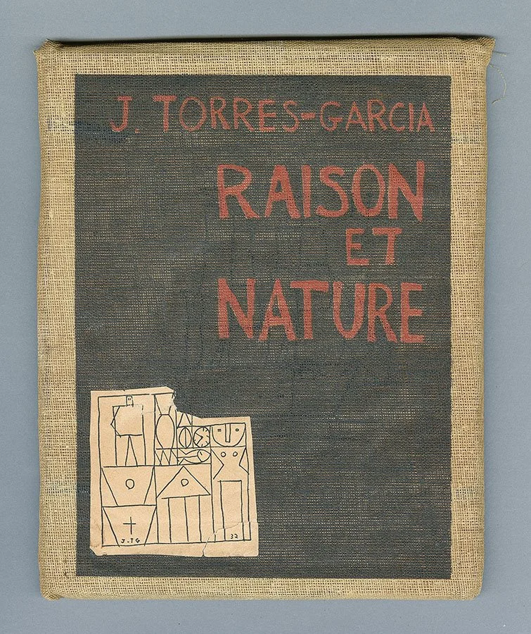 A fabric-covered book titled 'Raison et Nature' by J. Torres-Garcia features red text on a black background, with a small illustration of abstract geometric shapes and figures in the lower left corner.