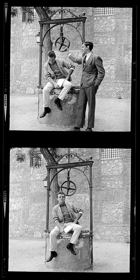 Two vintage-style black and white photographs of a man and a boy sitting on a large circular mill or water wheel. The photo is split into two frames. In the top frame, the man, dressed in a suit, stands while the boy, dressed casually, sits on the wheel and looks down. In the bottom frame, the man is seated on the wheel with one leg crossed over the other, and the boy is absent from this frame.