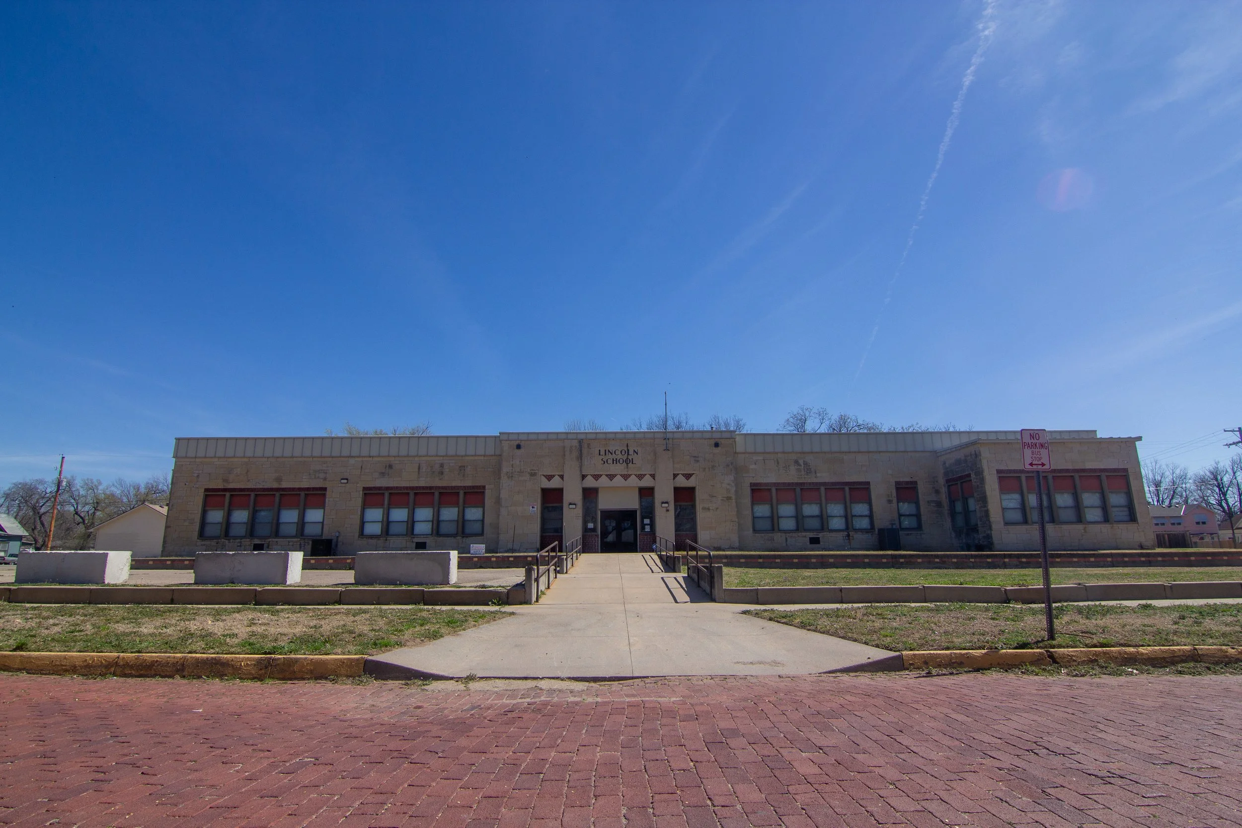 Front view of Lincoln School building under a clear blue sky with a sidewalk leading up to the entrance.