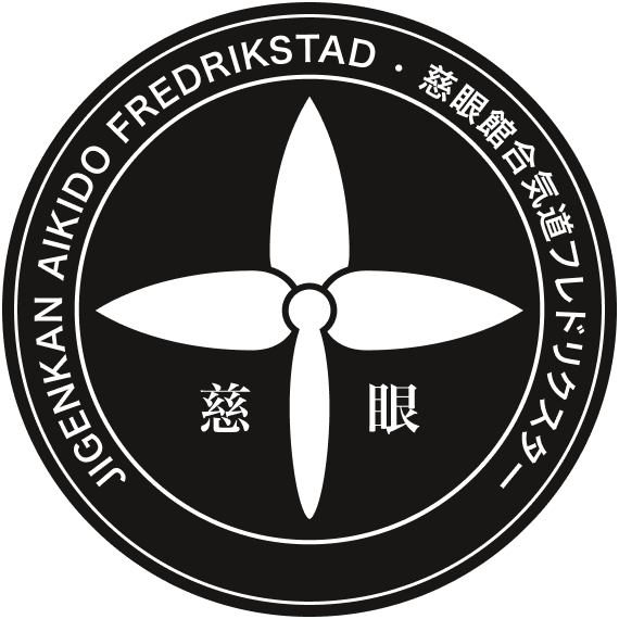 A circular logo with a black background and white design elements. It features a four-petaled flower or propeller in the center, with Japanese characters to the left and right. The outer ring contains text in English and Japanese.